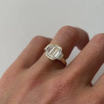 The Leonie Three Stone Engagement Ring on finger, against white background