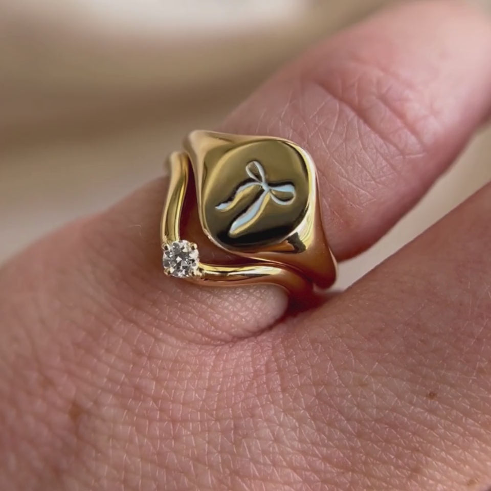 Video of the Blue Keepsake Signet Ring with a bow motif stacked with a curved diamond band on hand