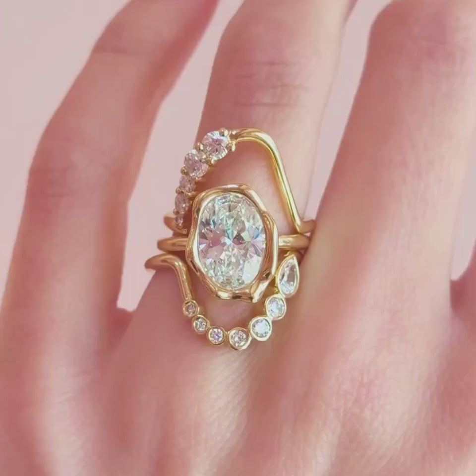 Video of The Abstract Bezel Oval Engagement Ring styled in different diamond band stacks on hand