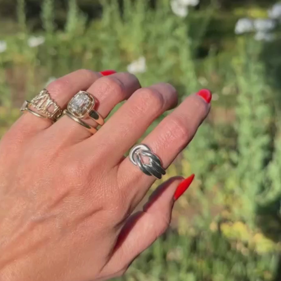 Video of hand against green plants wearing multiple Marrow Fine rings
