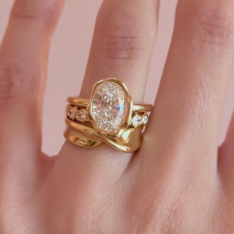 Video of The Abstract Bezel Oval Engagement Ring stacked with the Everyday Twist Ring and White Diamond Abstract Bezel Band on hand