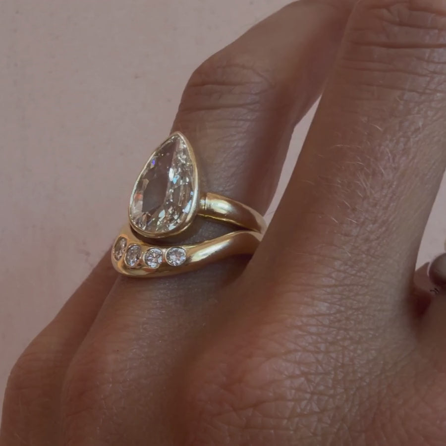 Video of the White Diamond Lola Bombe Band stacked with a pear diamond engagement ring on hand