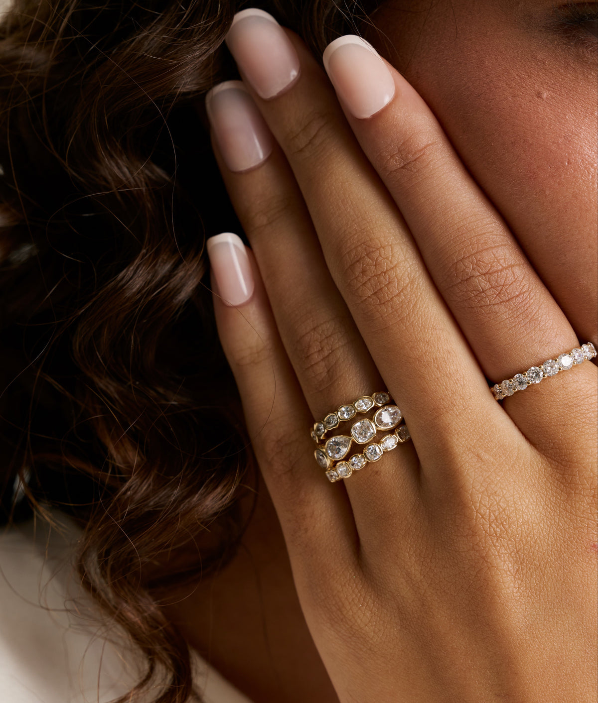 Model's hand near her face wearing white diamond stacking bands