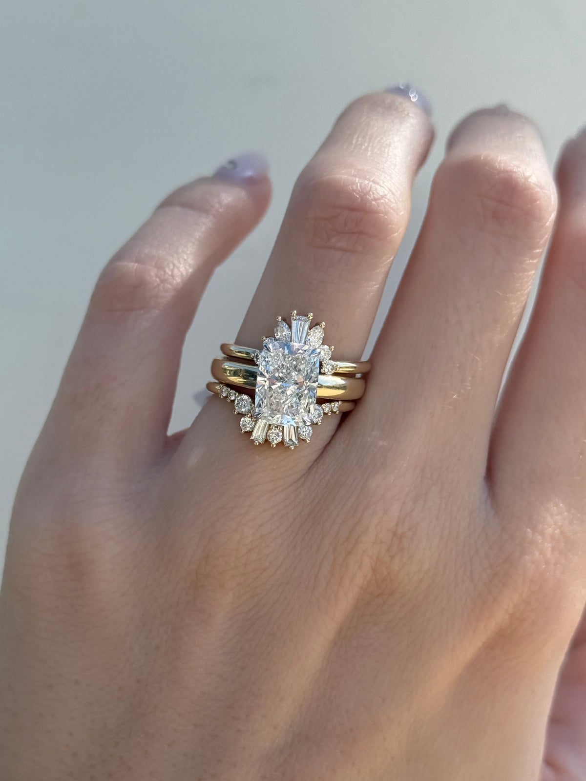 Diamond engagement ring with a halo of marquise diamonds stacked with bands on hand