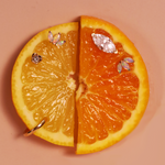 Sliced orange with earrings on a beige background