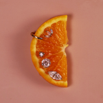 Orange wedge with diamond-shaped earrings on a beige background