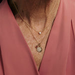 Necklace with charms worn by a person in a pink garment