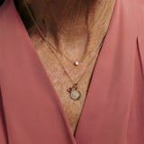 Necklace with charms worn by a person in a pink garment