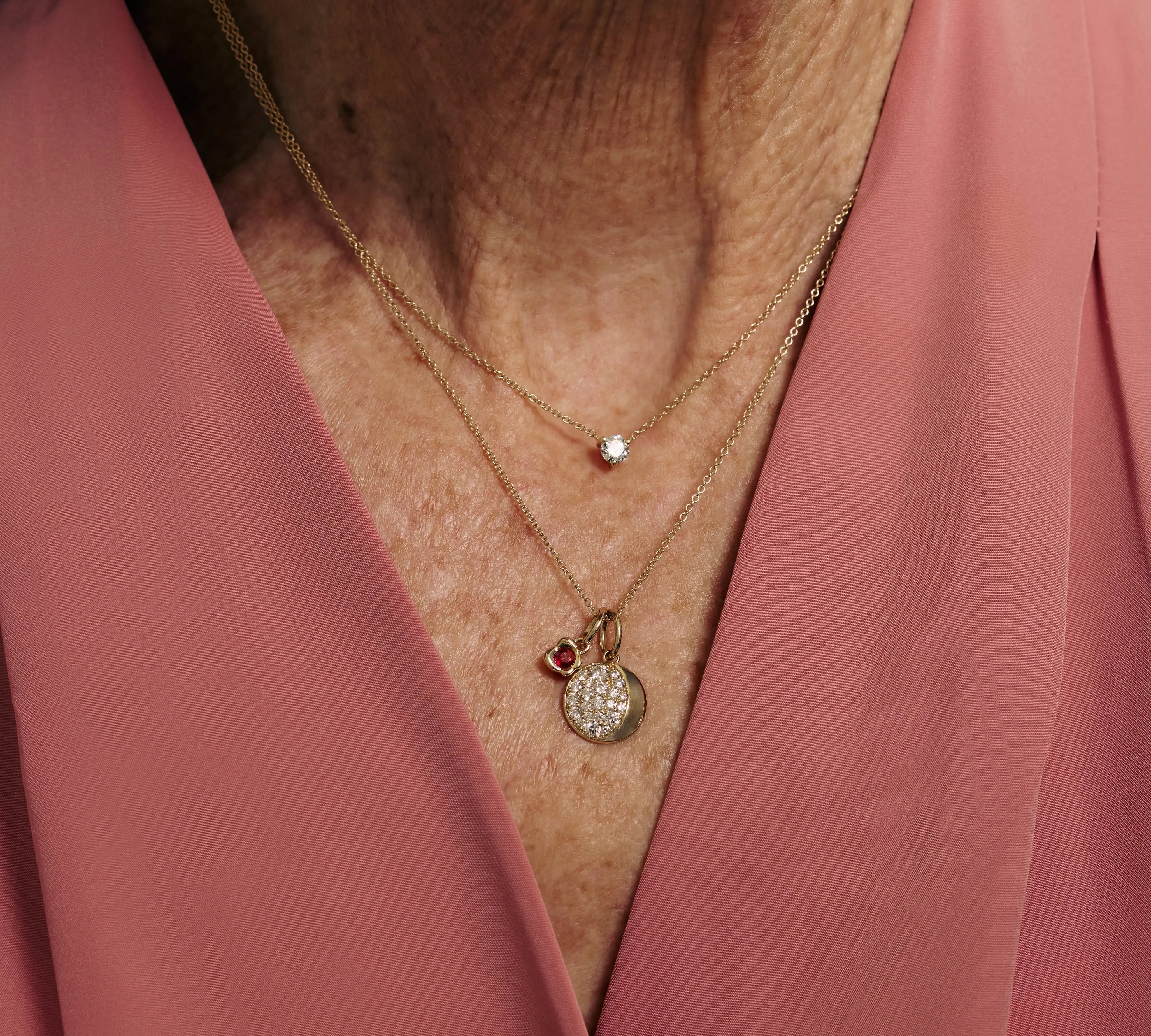 Necklace with charms worn by a person in a pink garment