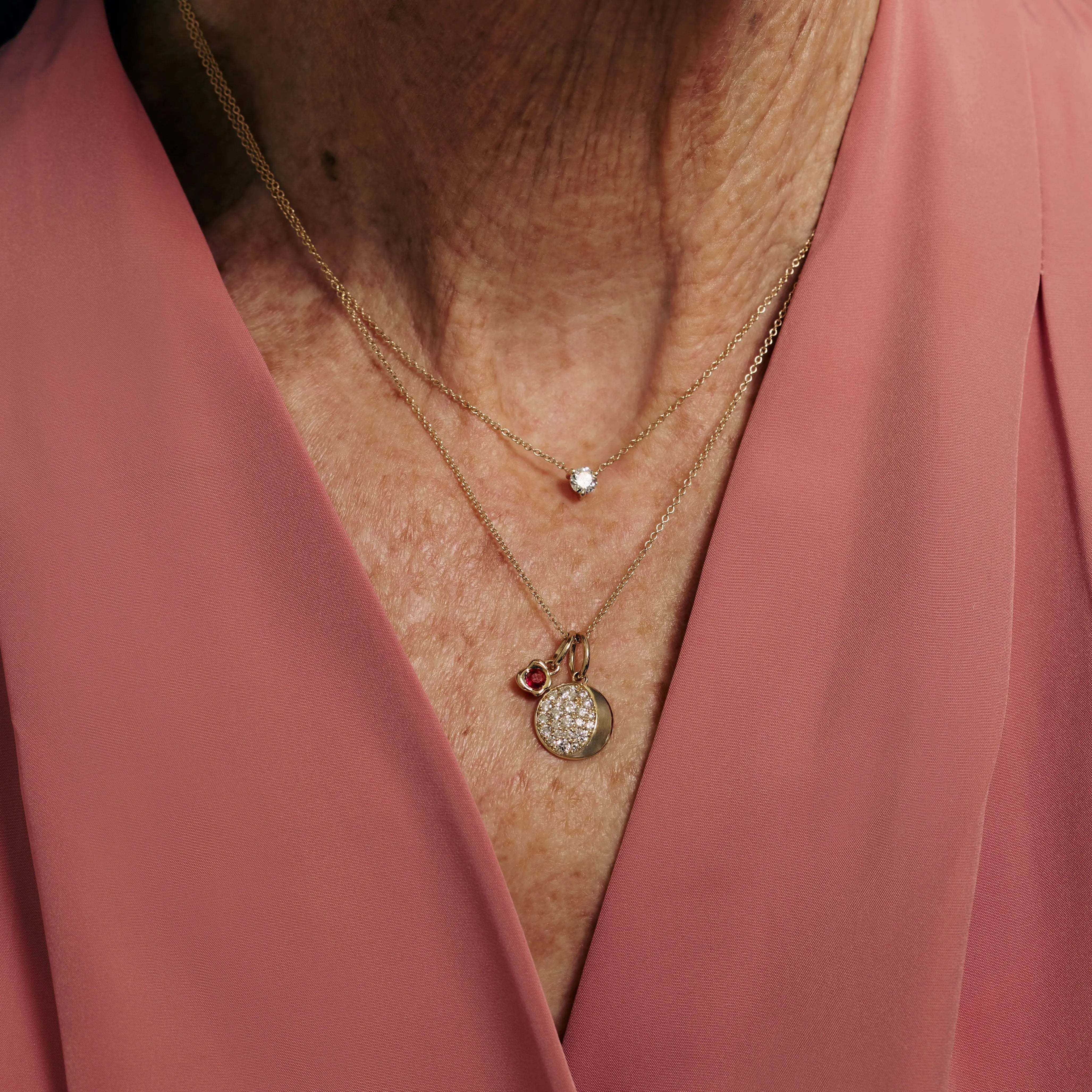 Necklace with charms worn by a person in a pink garment