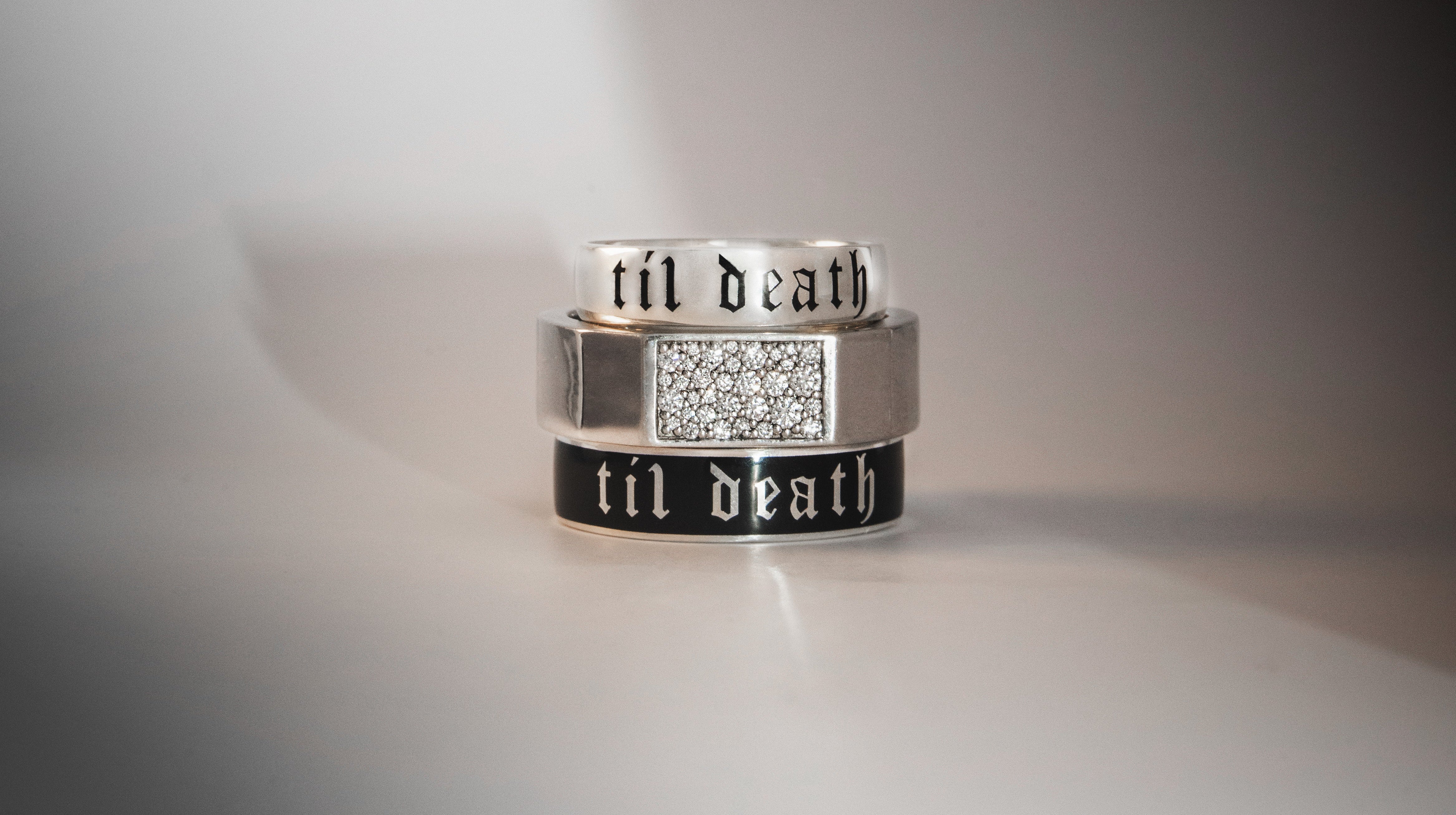 Three silver rings with engraved text on a reflective surface
