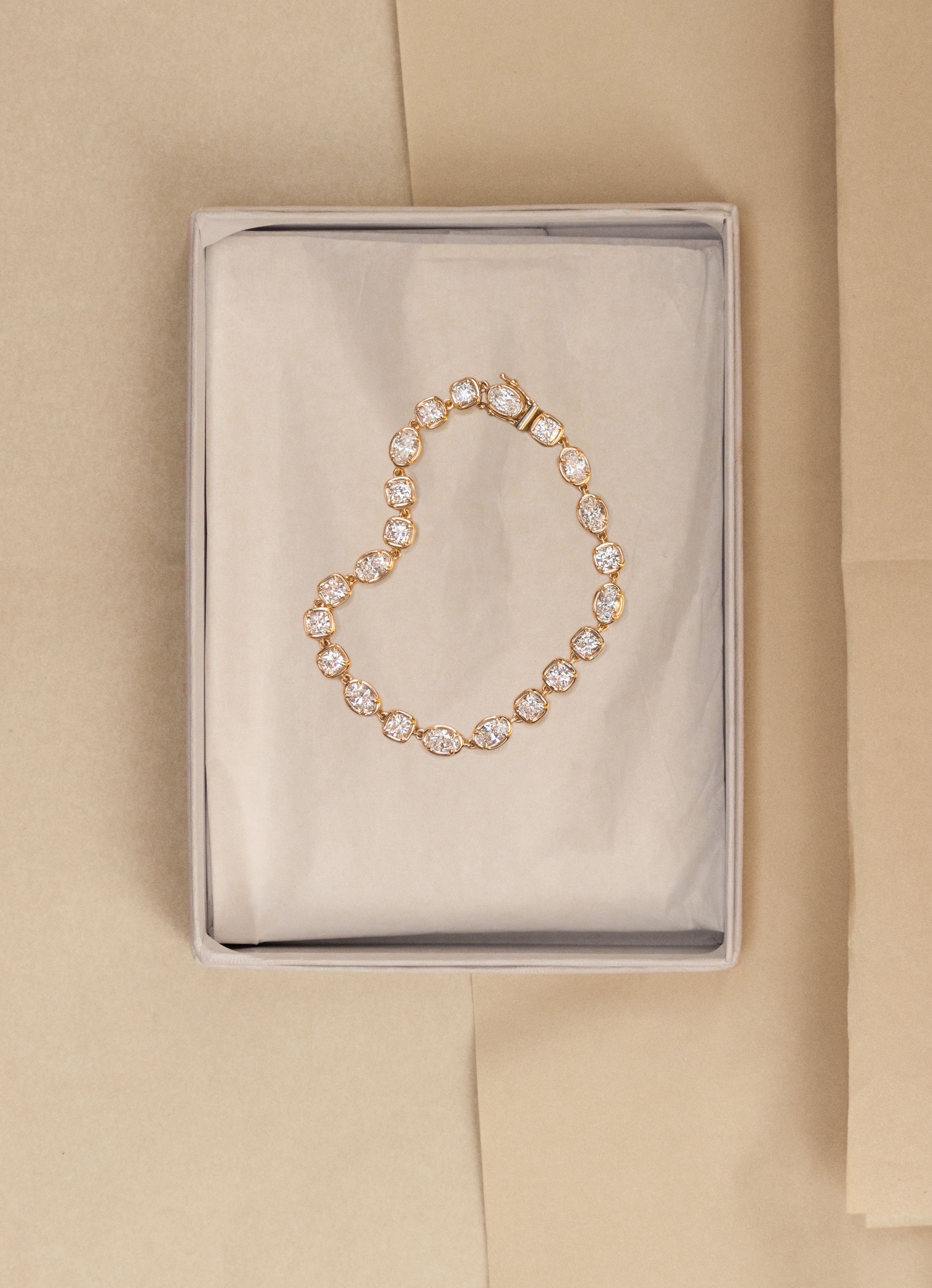 flat lay of mixed-shape diamond tennis bracelet laid on an open neutral white/gray box on a beige background