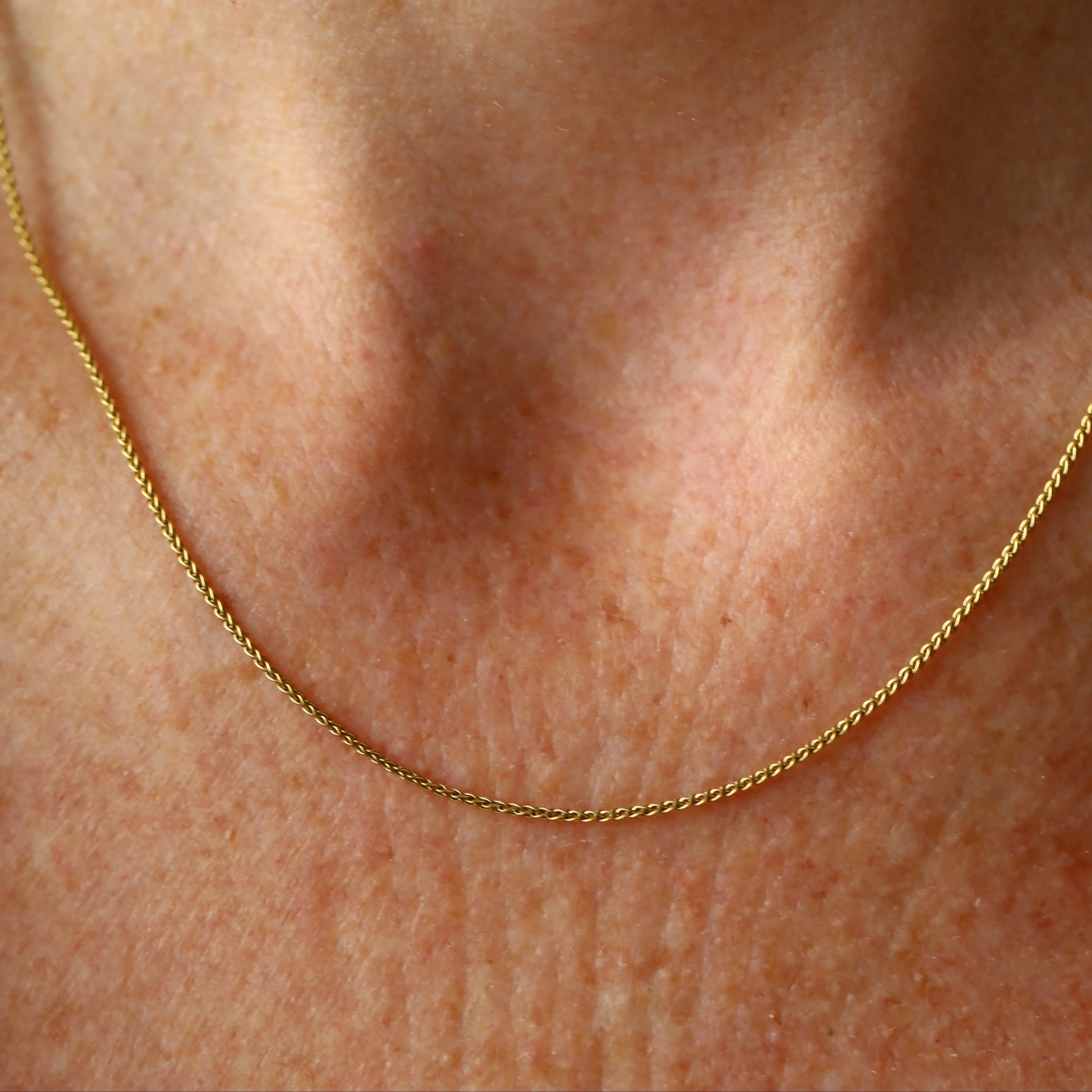Gold chain necklace on a person's neck
