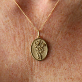 Gold necklace with a pendant featuring a floral design on a skin background