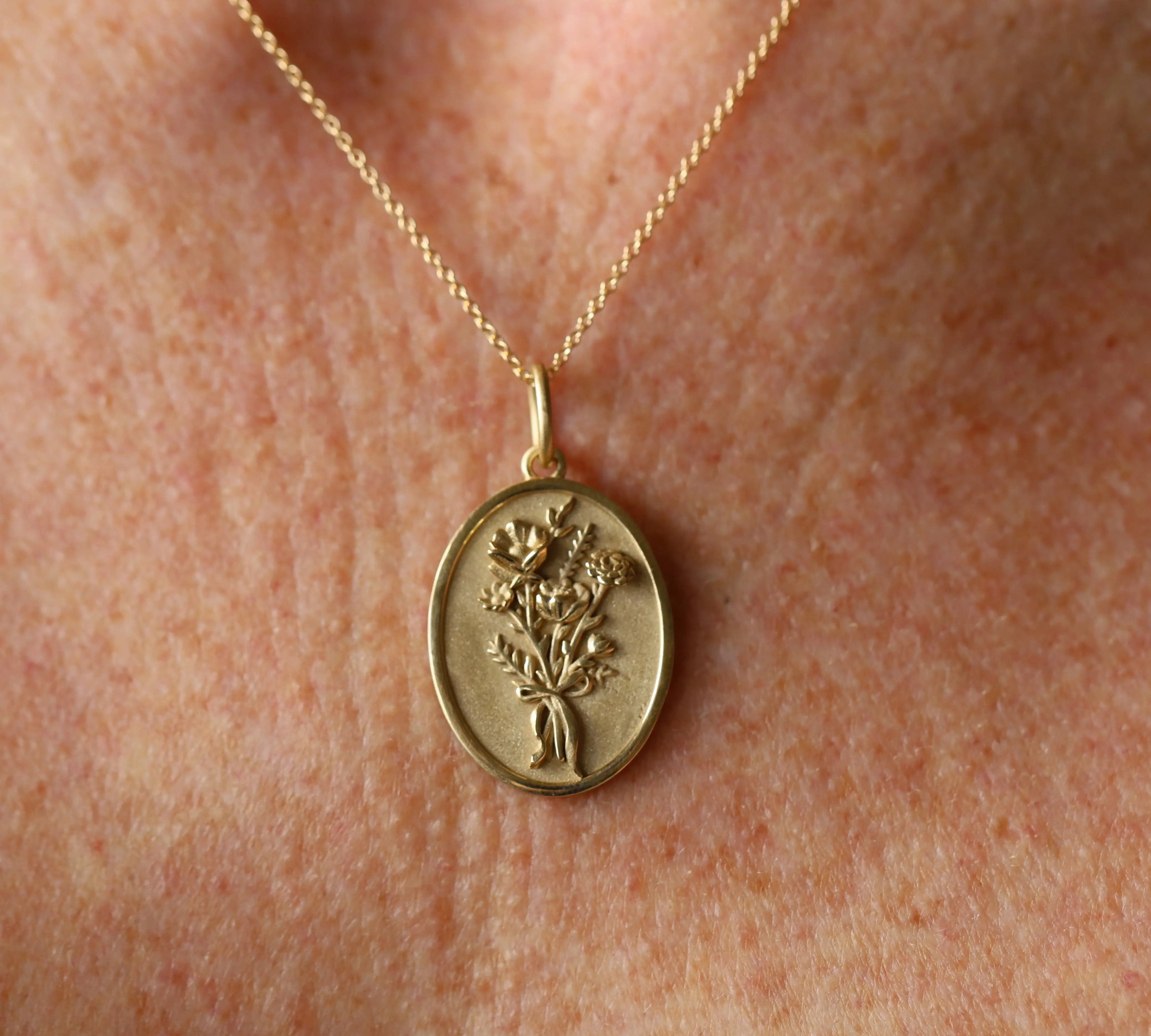 Gold necklace with a pendant featuring a floral design on a skin background