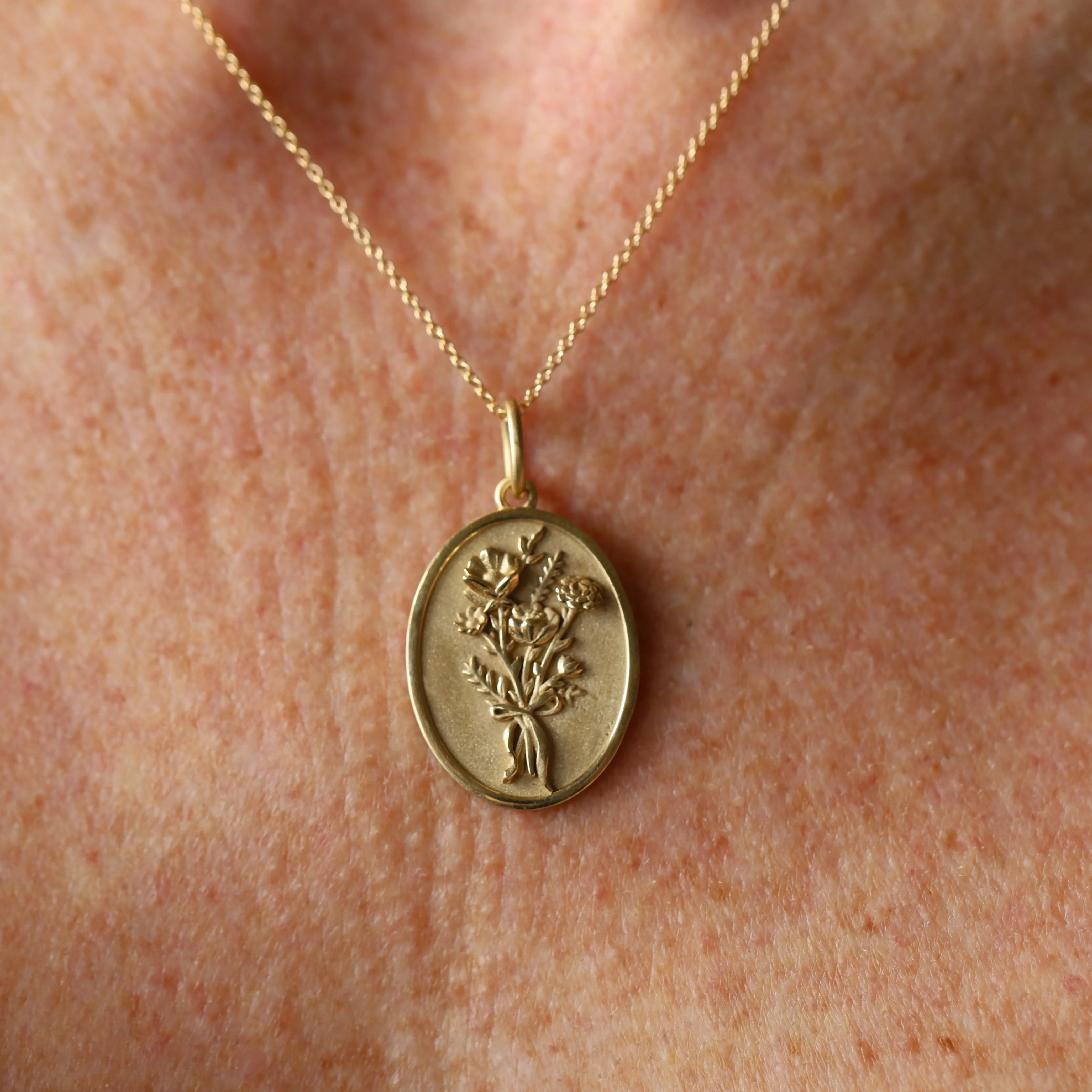 Gold necklace with a pendant featuring a floral design on a skin background